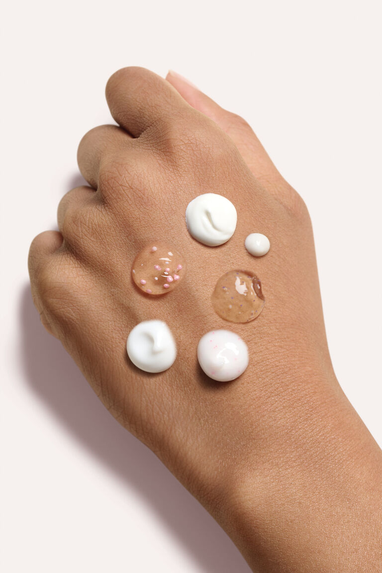 A woman's hand with drops of skin care products on it.