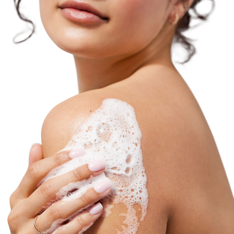 Medium-skinned model lathering limited-edition Lavender & Coconut Mary Kay Shower Gel on her shoulder