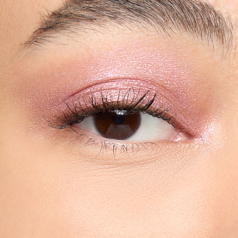 A model with a medium skin tone and brown eyes wears shade Pink Prisms.