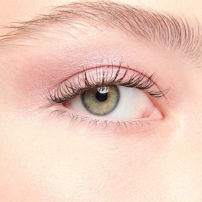 A model with a light skin tone and green eyes wears shade Pink Prisms.