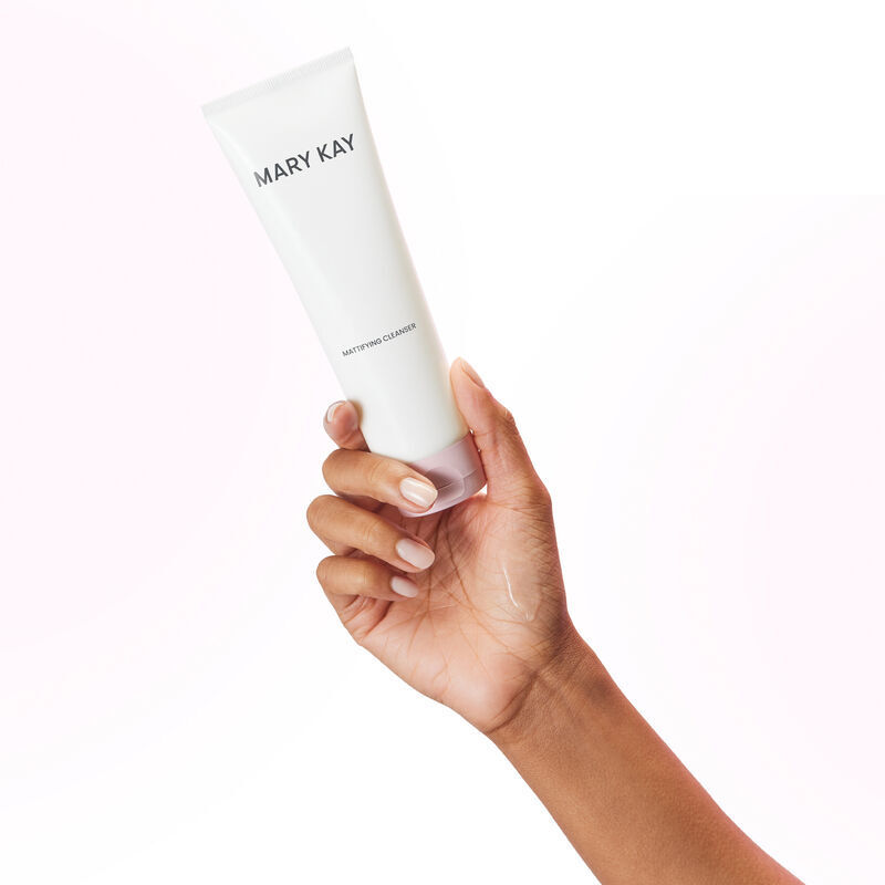 Hand holding tube of Mary Kay Mattifying Cleanser with product rub on the hand