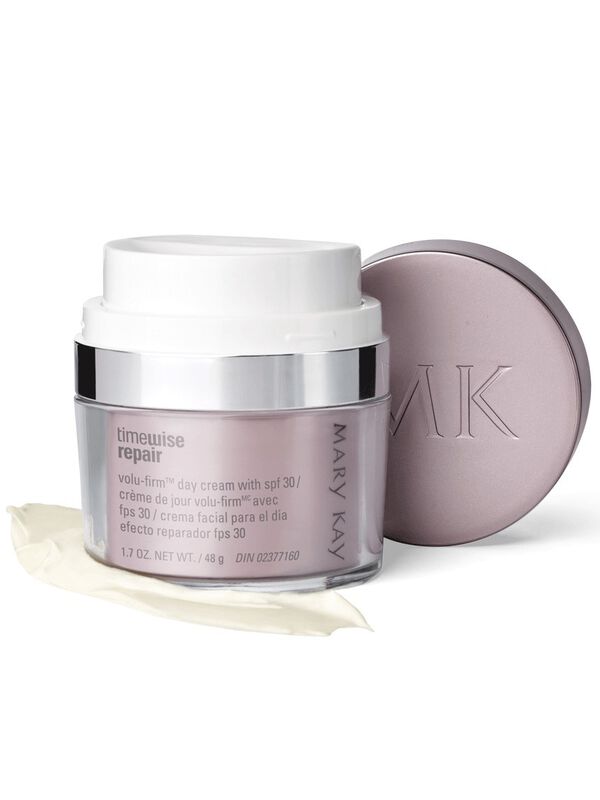 A jar of Mary Kay TimeWise Repair Volu-Firm Day Cream With SPF 30 with the lid propped against it, styled on top of a product rub. 