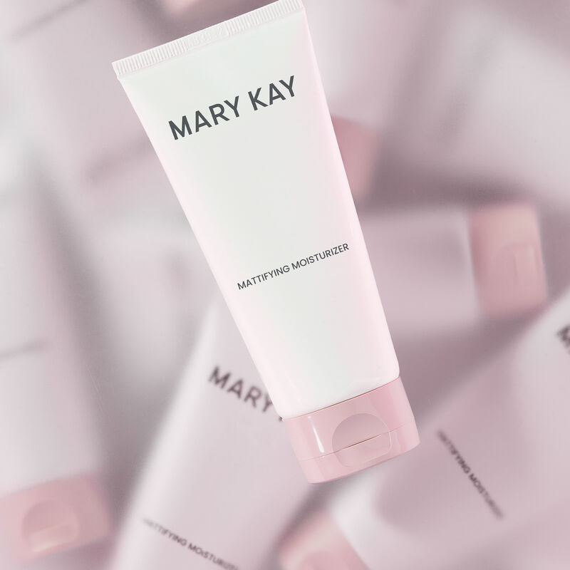 Tube of Mary Kay Mattifying Moisturizer in the forefront with multiple bottles of the same in blurry kaleidoscope effect