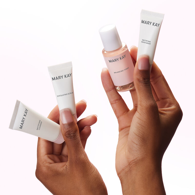 Pair of hands holding all four products in the Mary Kay Skin Care Mattifying Go Set image number null