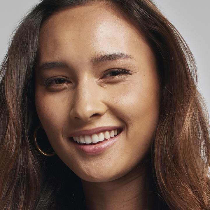 Brunette model smiling at the camera while wearing her Luminous foundation  shade.