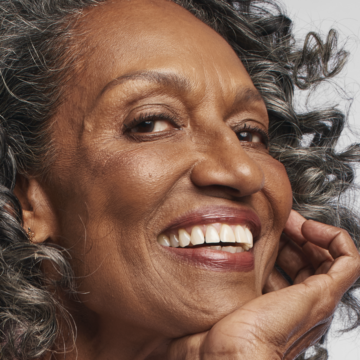 Deep skin tone model smiling at the camera while wearing Matte foundation.