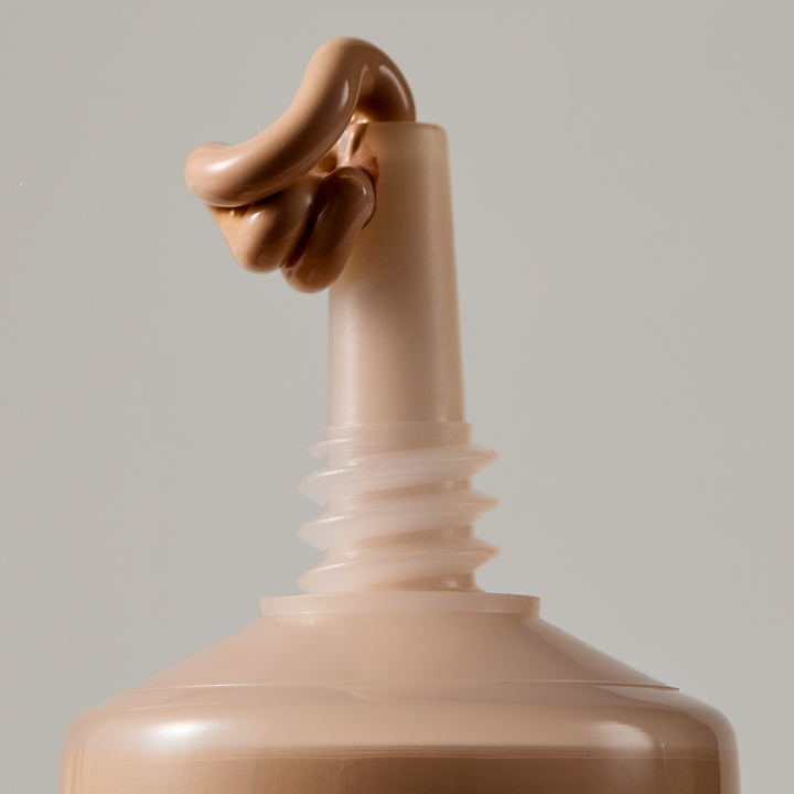 Macro shot of the needle-nose applicator with foundation dispensing from the tip.