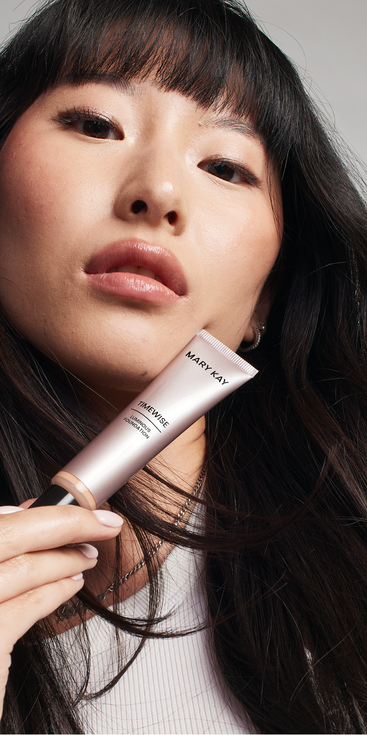 Asian model holding the foundation product while looking confidently at the  camera.