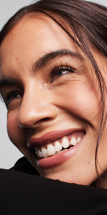 Model smiling and looking up, showing defined eyelashes