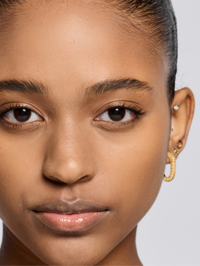 Deep skin tone model shown after applying foundation.