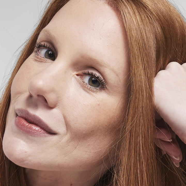Red-haired model looking at the camera wearing Luminous foundation with a  radiant finish.