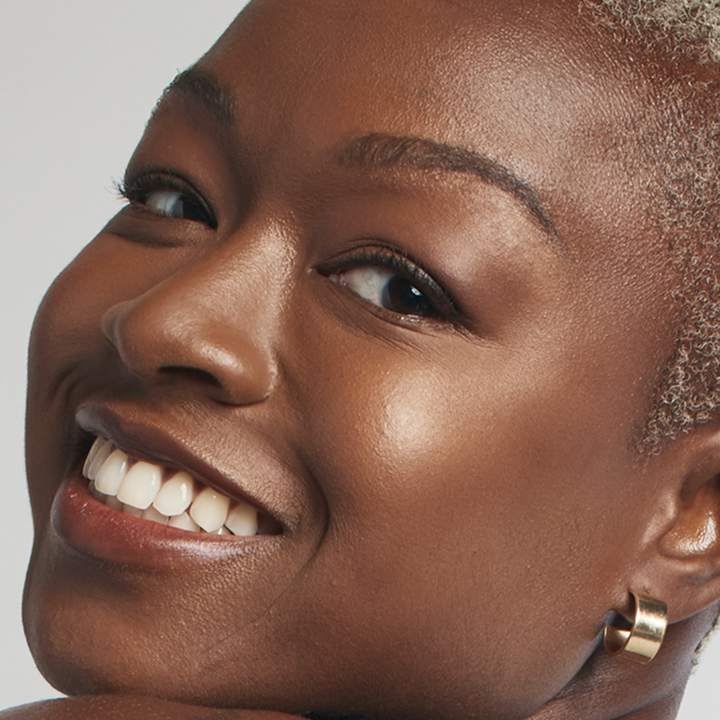 Deep skin tone model smiling at the camera.