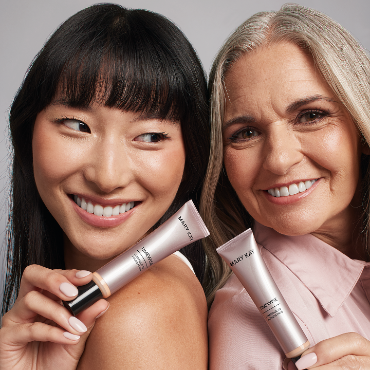 Asian model and mature model smiling while passing the foundation product to  each other.